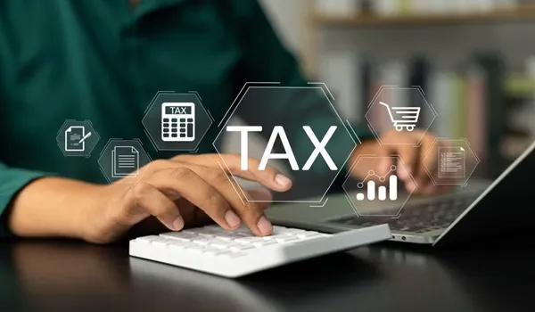 Taxes and charges on a Devanahalli apartment purchase – general information Person calculating GST, stamp duty and property taxes on a laptop